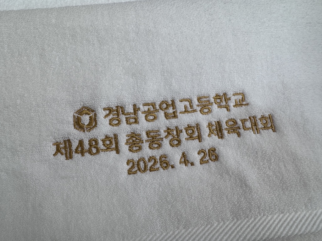 흰색 타월에 학교 문양과 동창회 체육대회 문구를 금색 실로 자수한 실제 사진