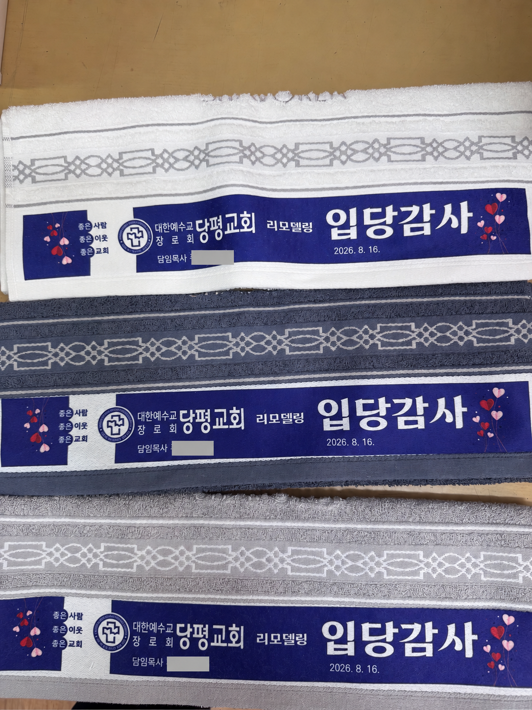 흰색·진회색·연회색 타월에 파란색 행사 도안을 전사 인쇄한 실제 작업 사진
